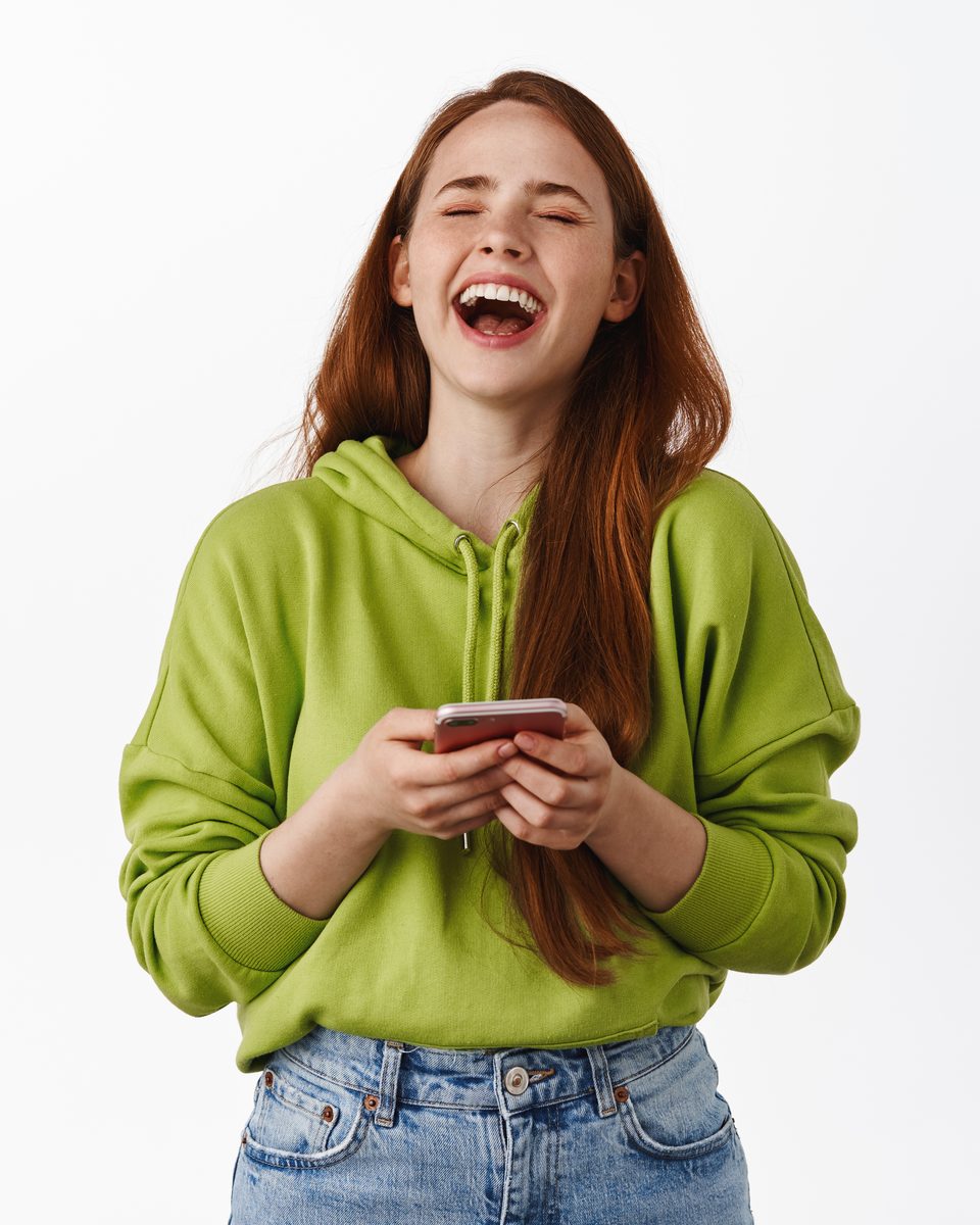 Mulher rindo enquanto olha o celular